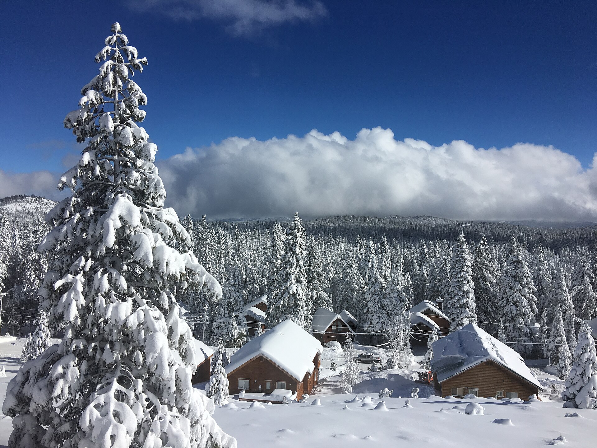 Snow-covered mountain cabins with deep drifts against timber walls