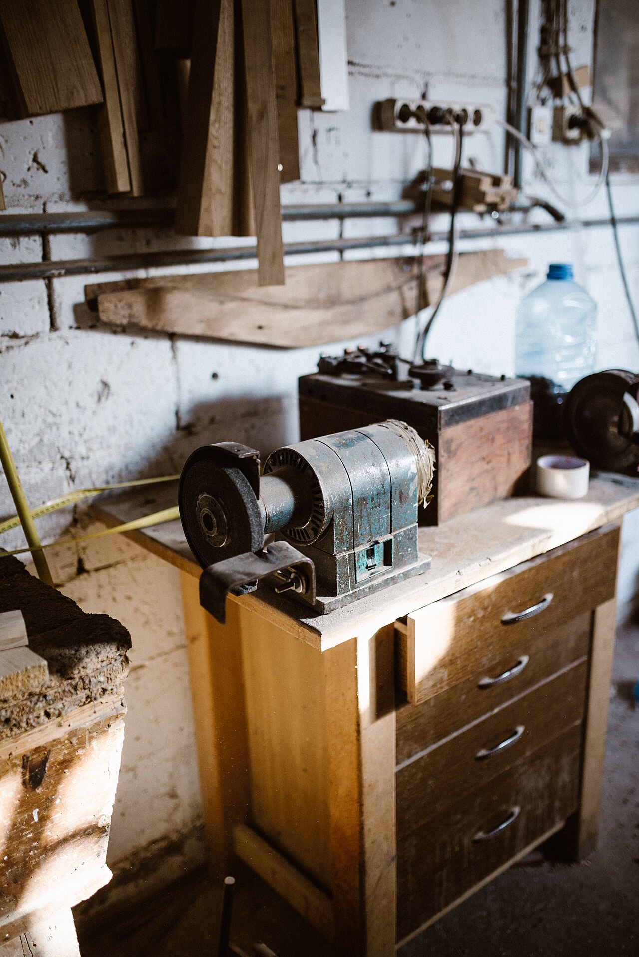 Bench grinder on a wooden workbench against a brick garage wall with tools