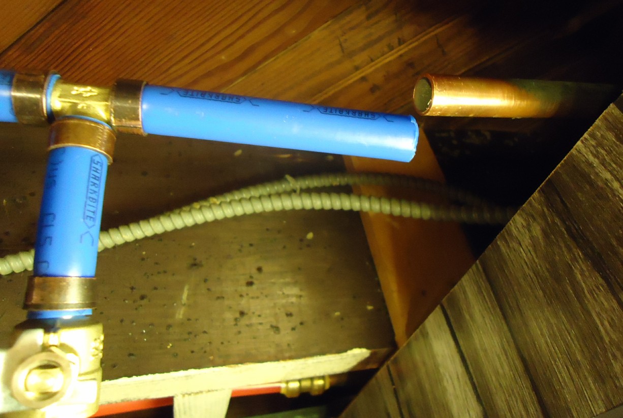 Blue PEX and copper water lines with valves in a basement ceiling
