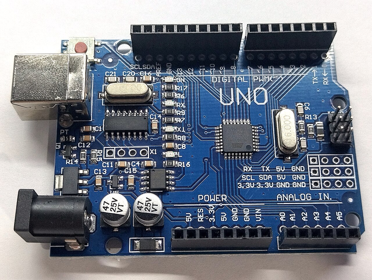 Top view of a blue Arduino Uno microcontroller board on a white background